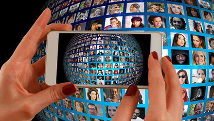Smartphone filmt Videowall mit Gesichtern